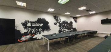 Parte da sala de imprensa com as mesas e a parede com imagens de Japo 2012