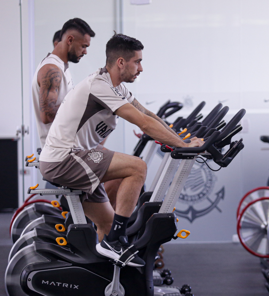 Igor Coronado e Raniele pedalando uma bicicleta ergomtrica dentro da academia do CT