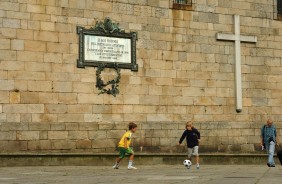 Crianças batem bola em frente a igreja na Espanha