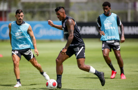 Paulinho toca a bola em treino do Corinthians, com Giuliano e Gil ao fundo