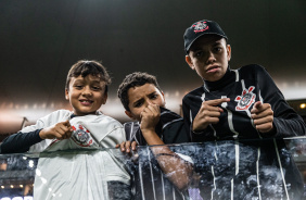 Jovens torcedores apontando e beijando o escudo do Corinthians na Neo Qumica Arena