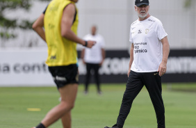 Mano Menezes caminhando no gramado do CT; Romero aparece correndo
