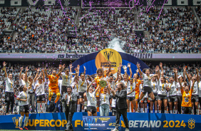 Jogadoras celebrando com o trofu da Supercopa; atrs aparece a torcida