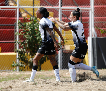 Carol Nogueira celebrando gol marcado enquanto Fernanda chega para abra��-la