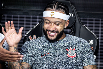 Memphis Depay sorrindo no banco de reservas no jogo contra o Velo Clube