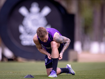 Charles amarrando a chuteira durante treino do Corinthians