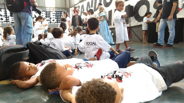 Criançada curtindo o evento enquanto jogadores se apresentam ao fundo
