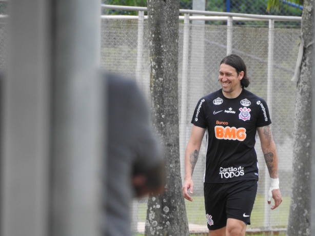 Cássio sorridente com mão enfaixada caminhando no CT do Timão