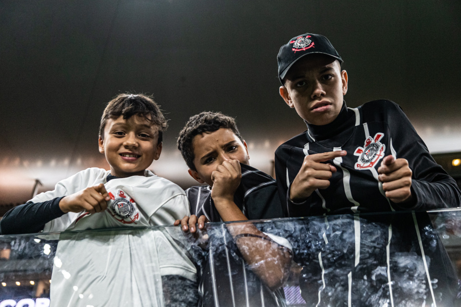 Jovens torcedores apontando e beijando o escudo do Corinthians na Neo Qumica Arena